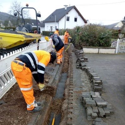 Bauarbeiten für den Glasfaserausbau in der Gemeinde, Arbeiter verlegen Kabel und gestalten die Infrastruktur neu.