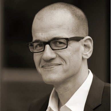 Professioneller Mann mit Brille in Anzug, symbolisiert die Expertise von Unsere Grüne Glasfaser im Bereich digitale Infrastruktur.