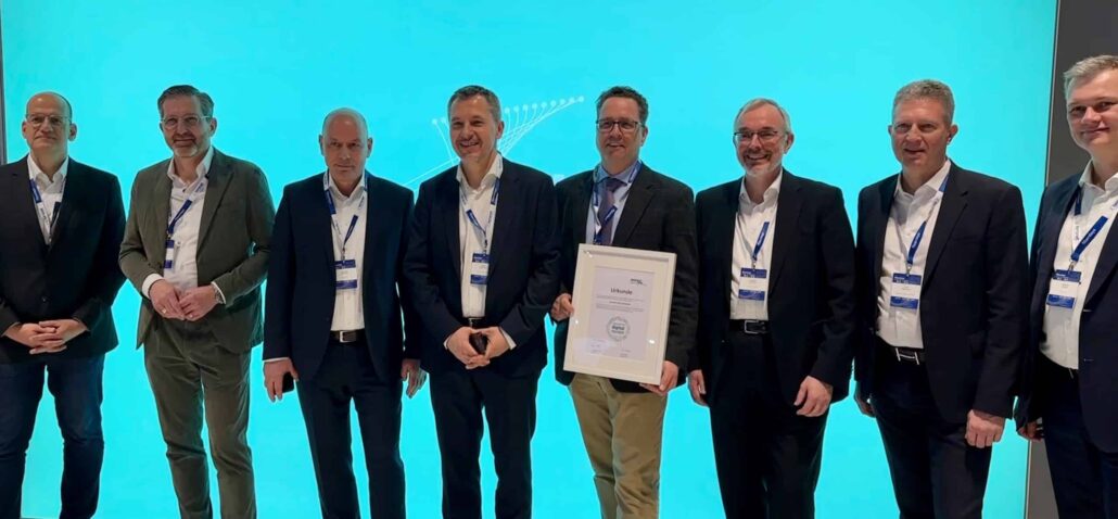 Geschäftsführer von Unsere Grüne Glasfaser präsentieren eine Auszeichnung auf einer Fachveranstaltung für digitale Infrastruktur.