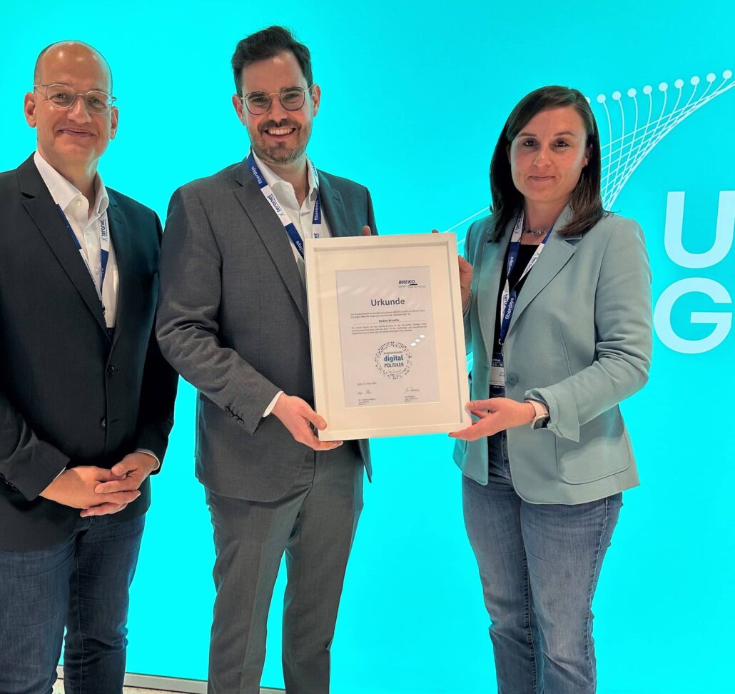 Mitarbeiter von Unsere Grüne Glasfaser präsentieren stolz eine Auszeichnung für digitale Innovation.