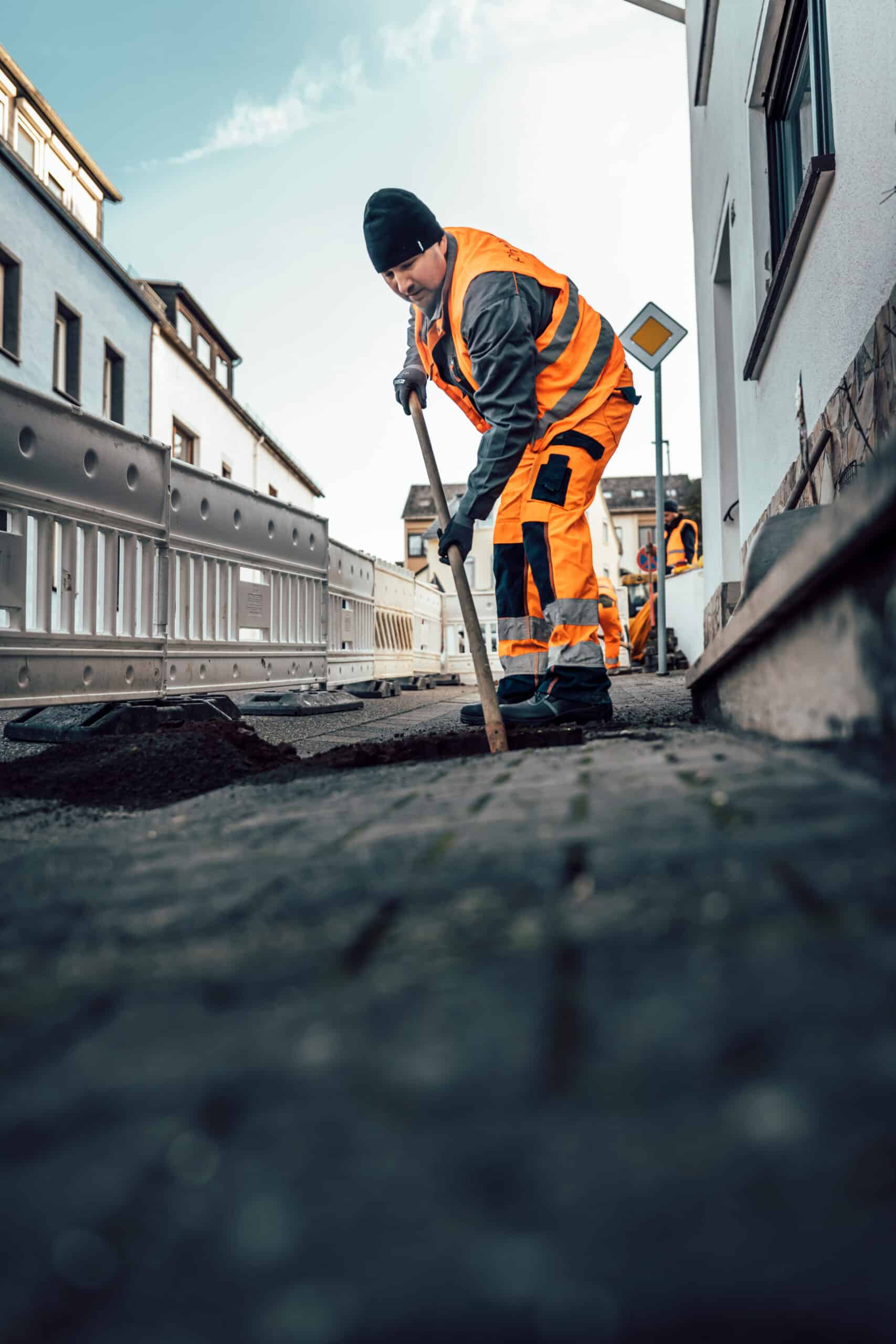 Arbeiter verlegt Glasfaserleitungen auf einer Baustelle in einem urbanen Gebiet für Unsere Grüne Glasfaser.