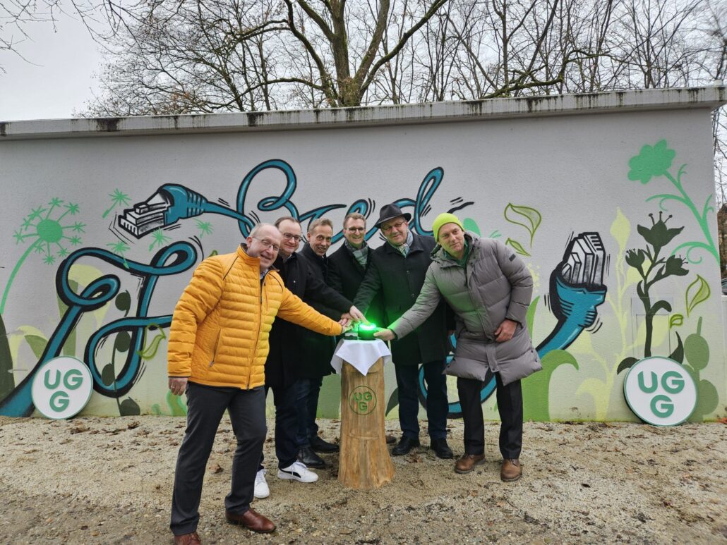Feierliche Eröffnung von Unsere Grüne Glasfaser mit Beteiligten vor einem kreativen Wandgemälde.