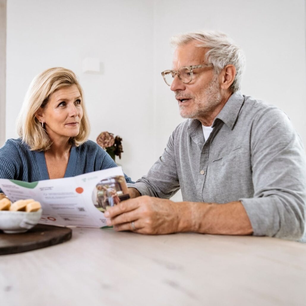 Älteres Paar bespricht Informationen zu Glasfaseranschlüssen am Tisch, um die Vorteile von schnellerem Internet zu erkunden.