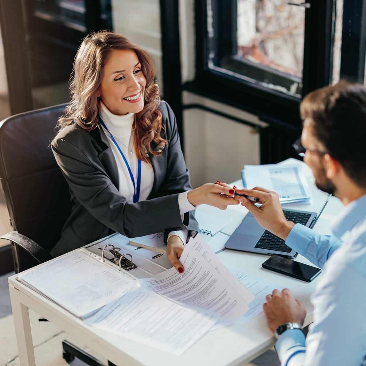 Frau im Büro übergibt Dokumente an einen Kollegen, symbolisiert Zusammenarbeit bei Unsere Grüne Glasfaser.
