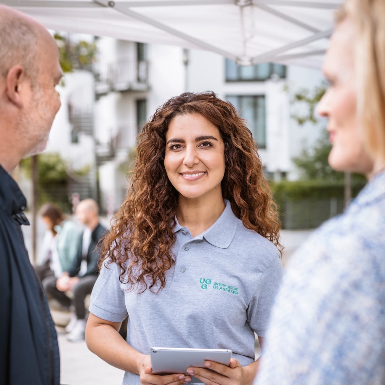 Beratungsgespräch mit einer Mitarbeiterin von Unsere Grüne Glasfaser am Informationsstand für nachhaltige Internetlösungen.