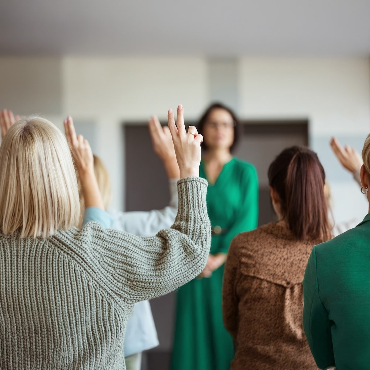 Teilnehmerinnen bei einer Informationsveranstaltung zu "Unsere Grüne Glasfaser" heben die Hände für Fragen.