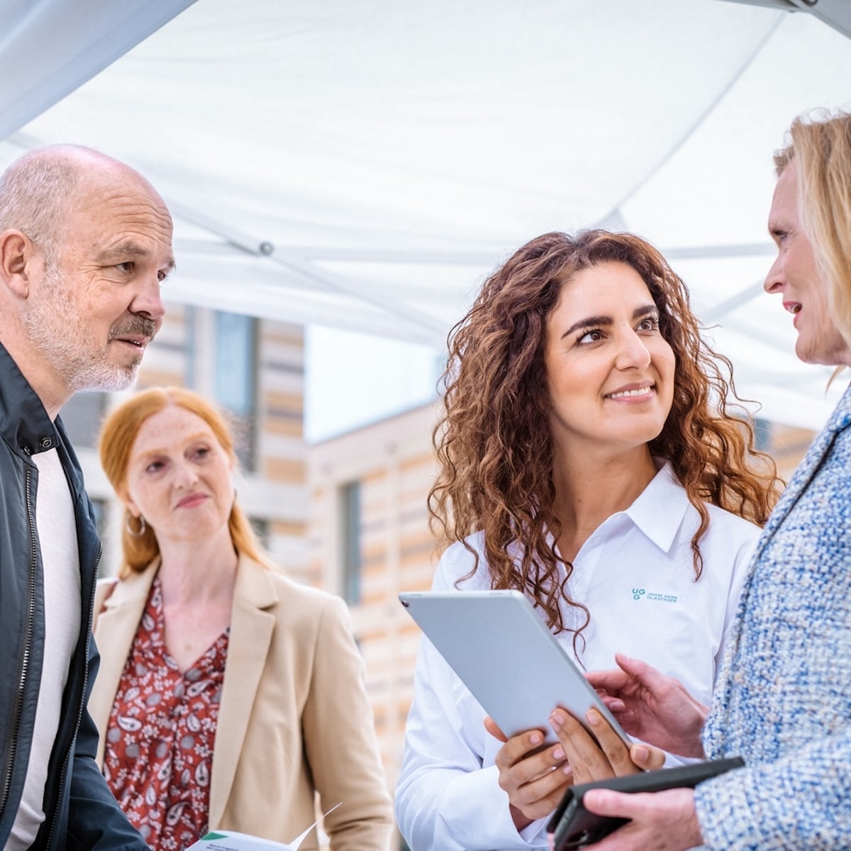 Beratungsgespräch über Glasfaserlösungen von Unsere Grüne Glasfaser mit interessierten Kunden im Freien.