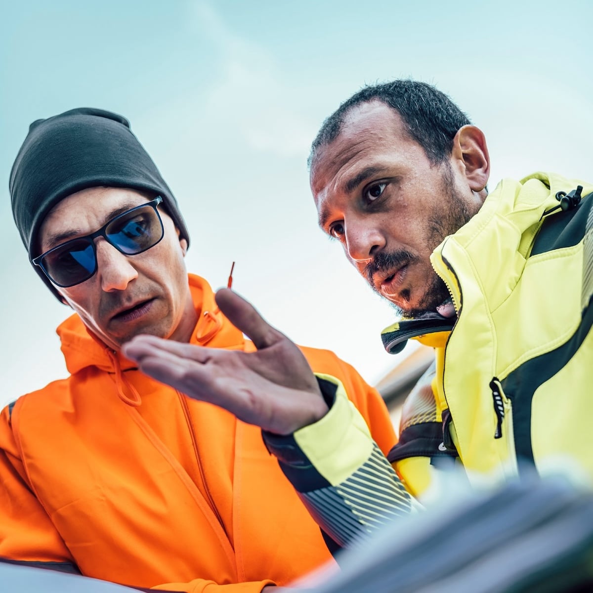 Zwei Techniker besprechen Pläne für den Ausbau von Glasfaserleitungen für Unsere Grüne Glasfaser im Freien.