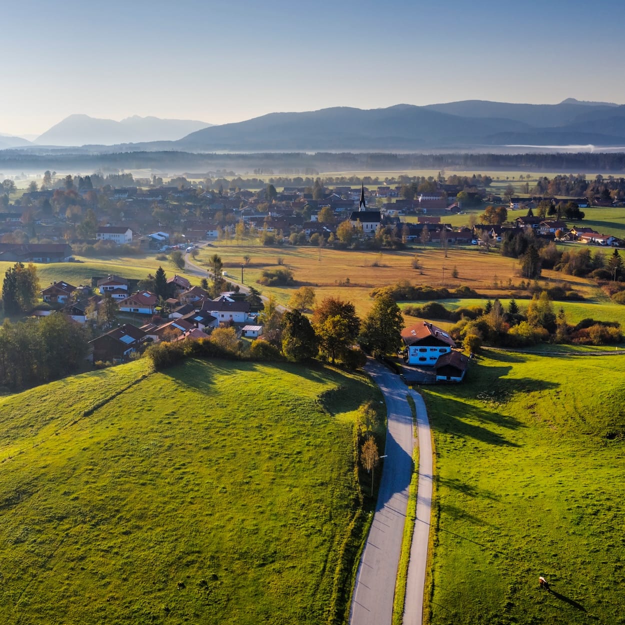 Landschaft mit ländlichem Dorf, sanften Hügeln und Glasfaseranbindung für eine zukunftssichere Internetversorgung.