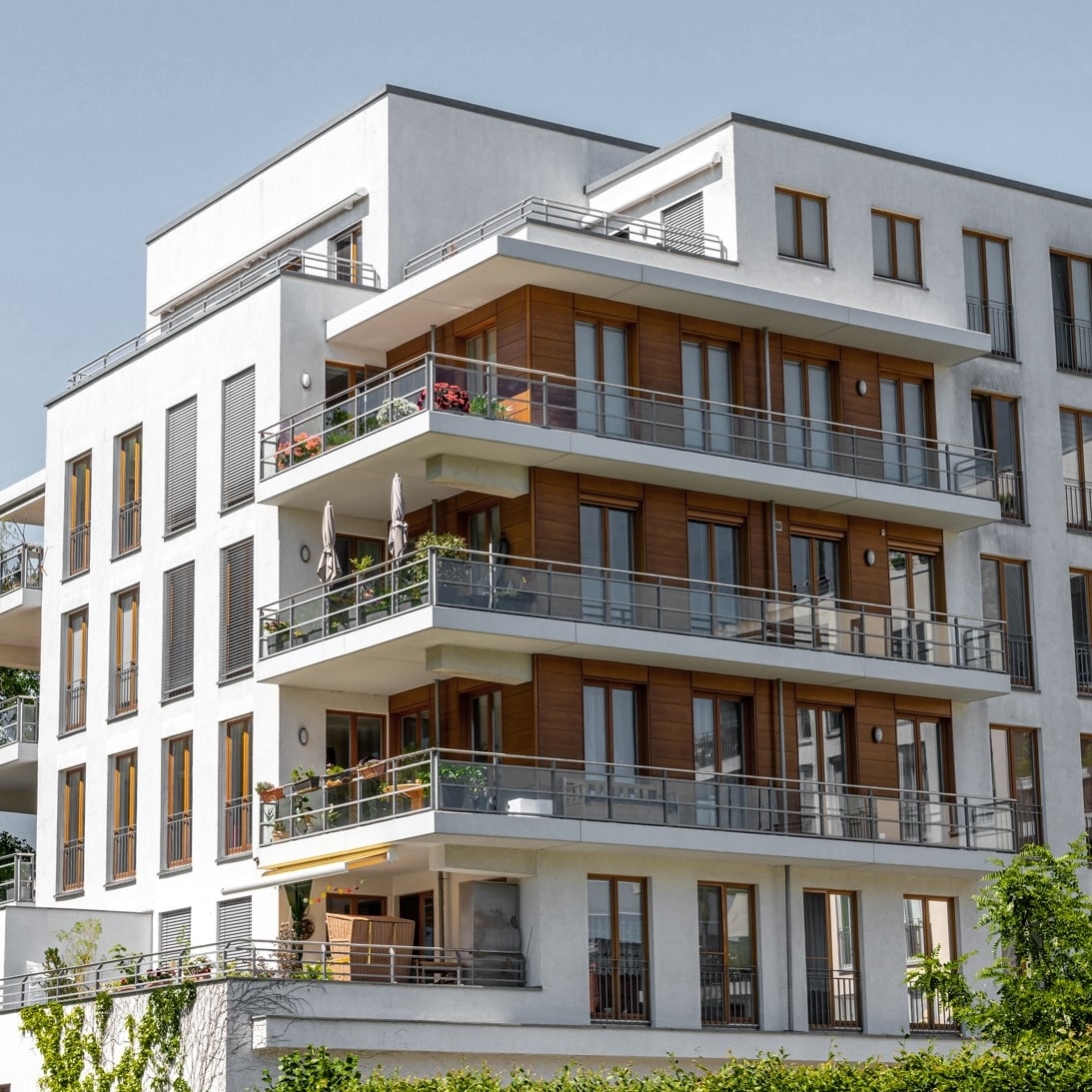 Moderne Wohnanlage mit Balkonen und Pflanzen, ideal für Glasfaseranschlüsse von Unsere Grüne Glasfaser.