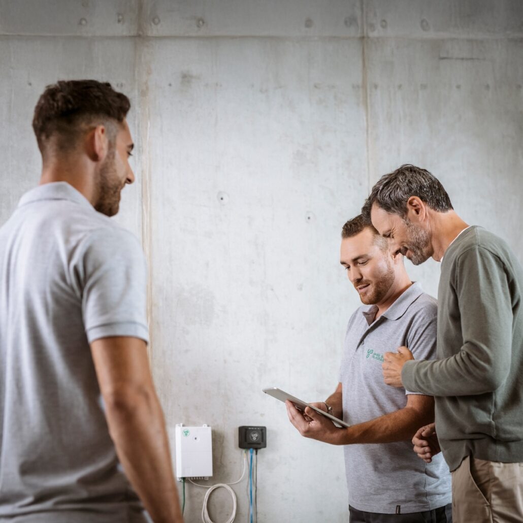 Techniker von Unsere Grüne Glasfaser prüfen Installationsdetails für schnelle Internetverbindungen in modernen Räumlichkeiten.
