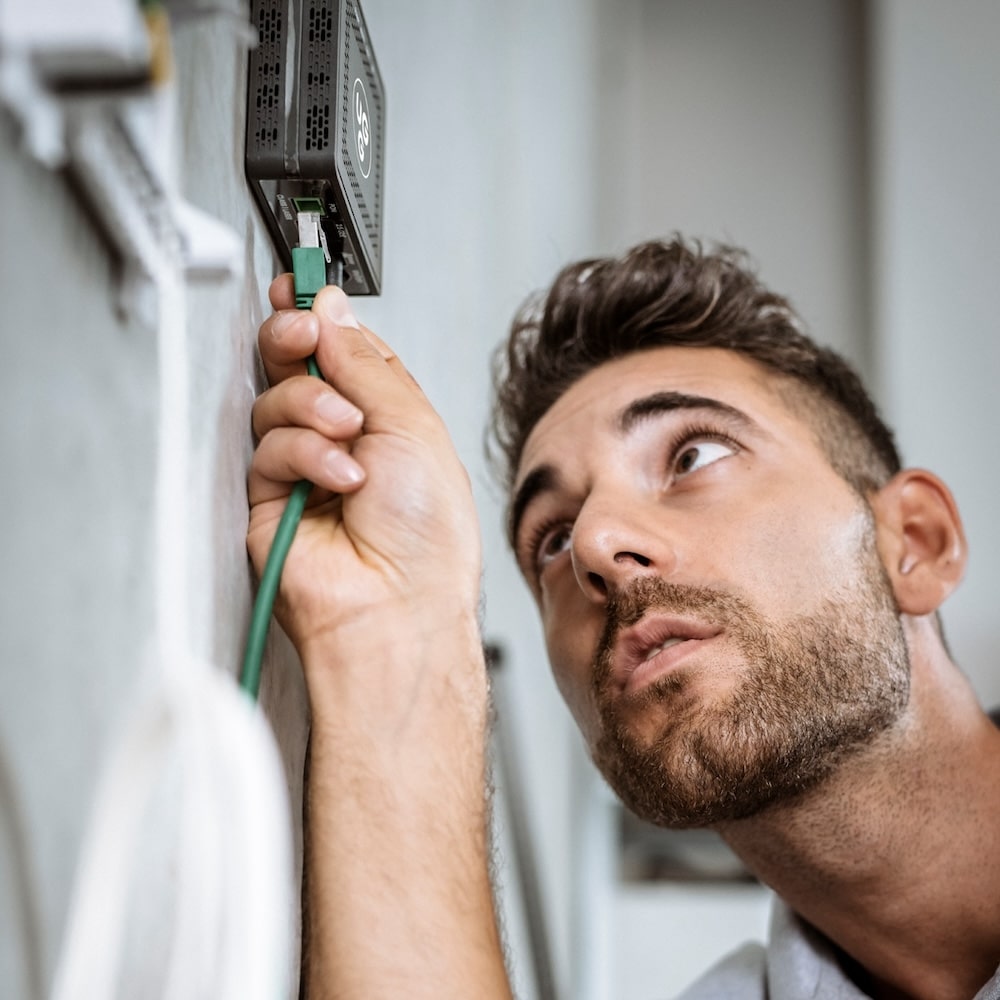 Techniker installiert Glasfaseranschluss und prüft die Verbindung für Unsere Grüne Glasfaser. Schnelles Internet für alle.