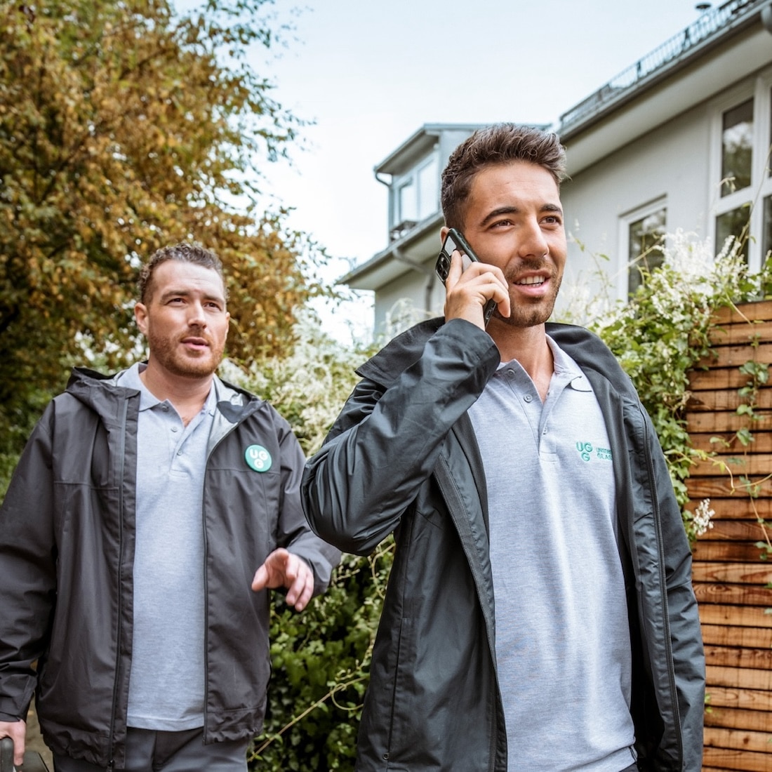 Techniker von Unsere Grüne Glasfaser bei der Arbeit, telefonierend und auf dem Weg zu einem Kunden.